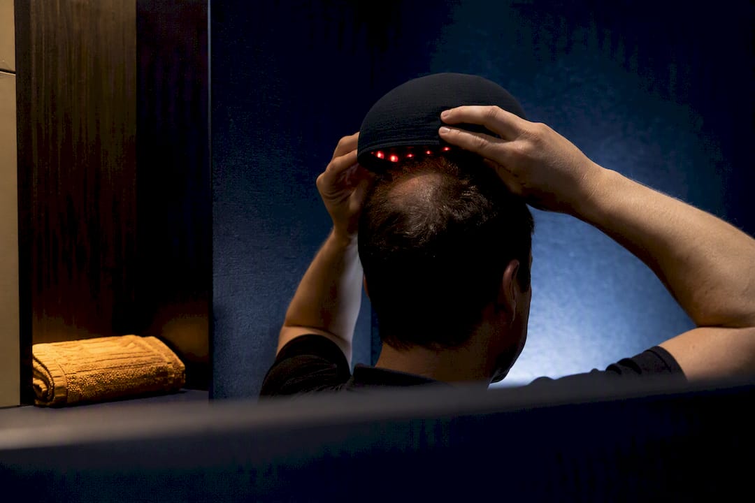 Person positioning a laser therapy cap