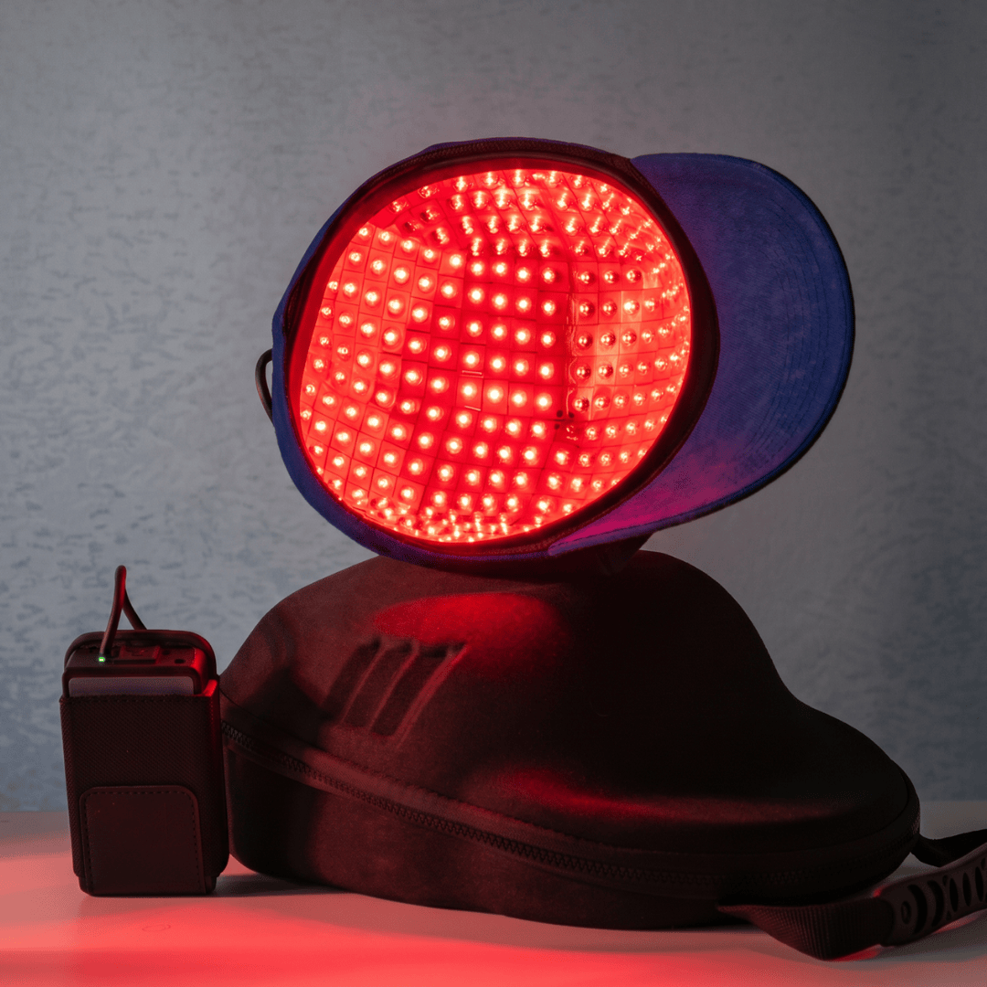 Laser Hair Growth Cap lit up showing battery and carry case by LIVDOR