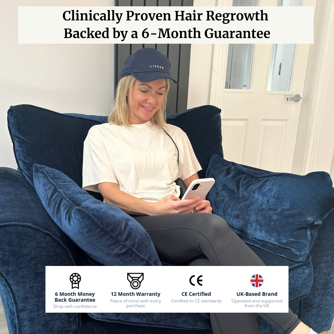 Lady wearing laser hair growth cap relaxing on a sofa looking at her phone.