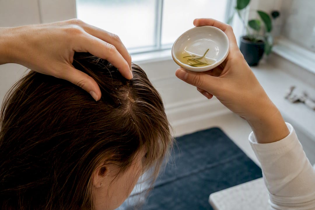 Hands applying rosemary oil to scalp